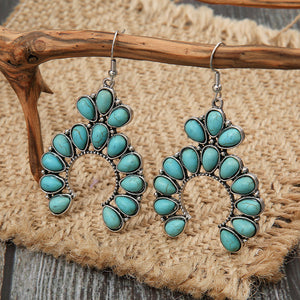 Turquoise crescent dangle earrings with alloy setting and teardrop stones.