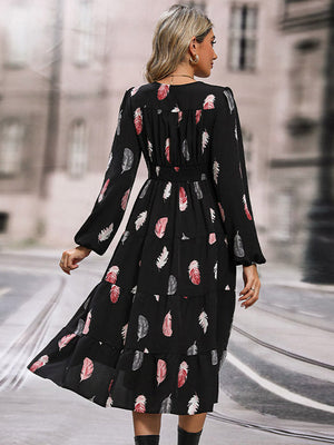 Black tiered midi dress with feather print, long sleeves, and smocked waist.
