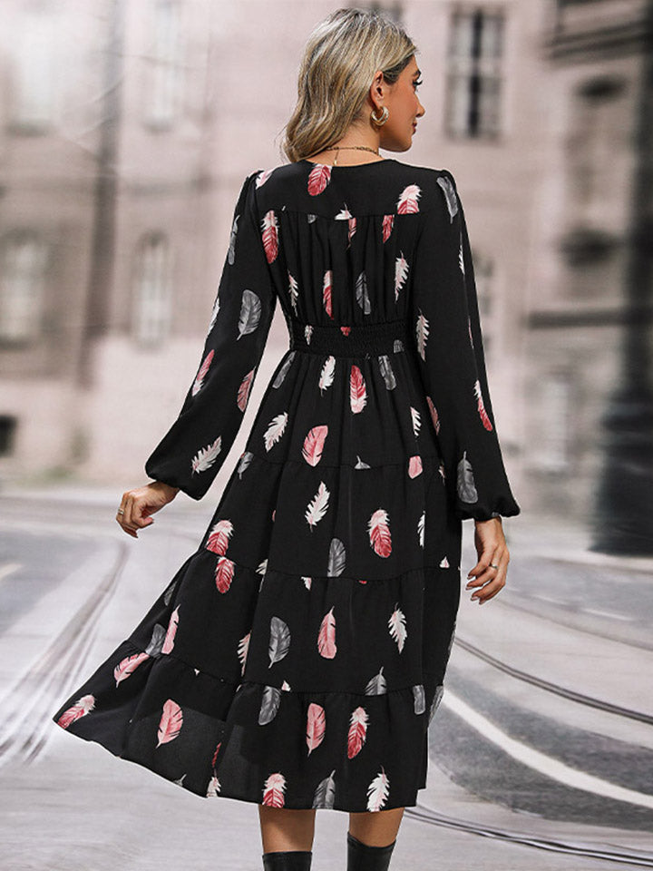 Black tiered midi dress with feather print, long sleeves, and smocked waist.