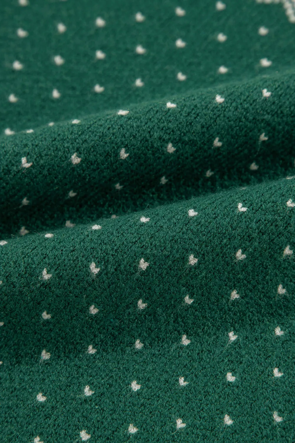 Dark green knit sweater with a white snowflake Fair Isle pattern.