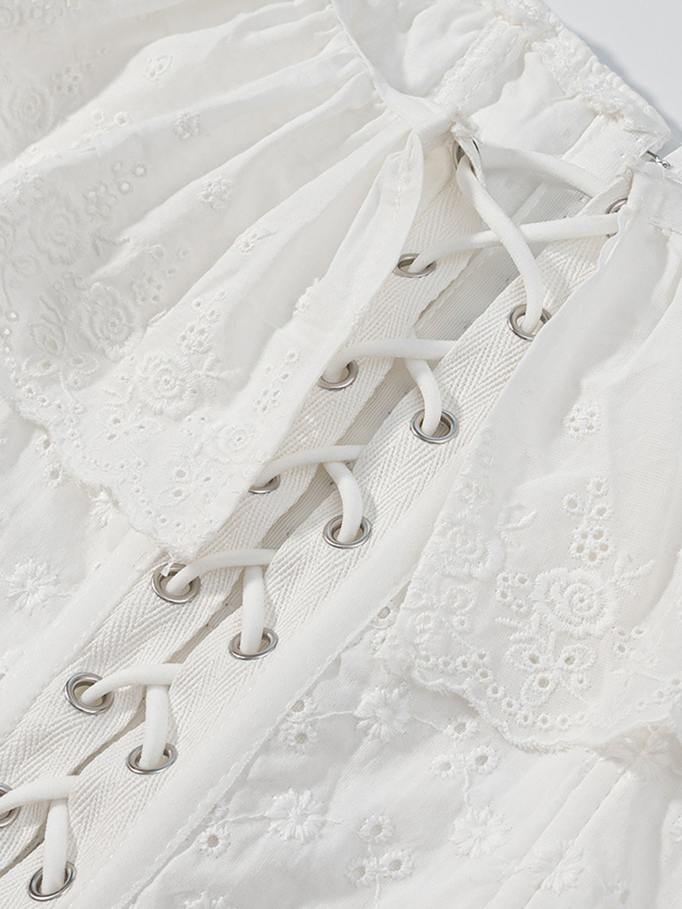 White eyelet tank top with ruffle trim and corset lace-up detail