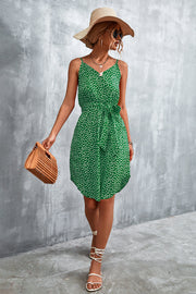 Green daisy print slip dress with tie waist, V-neck, and spaghetti straps.