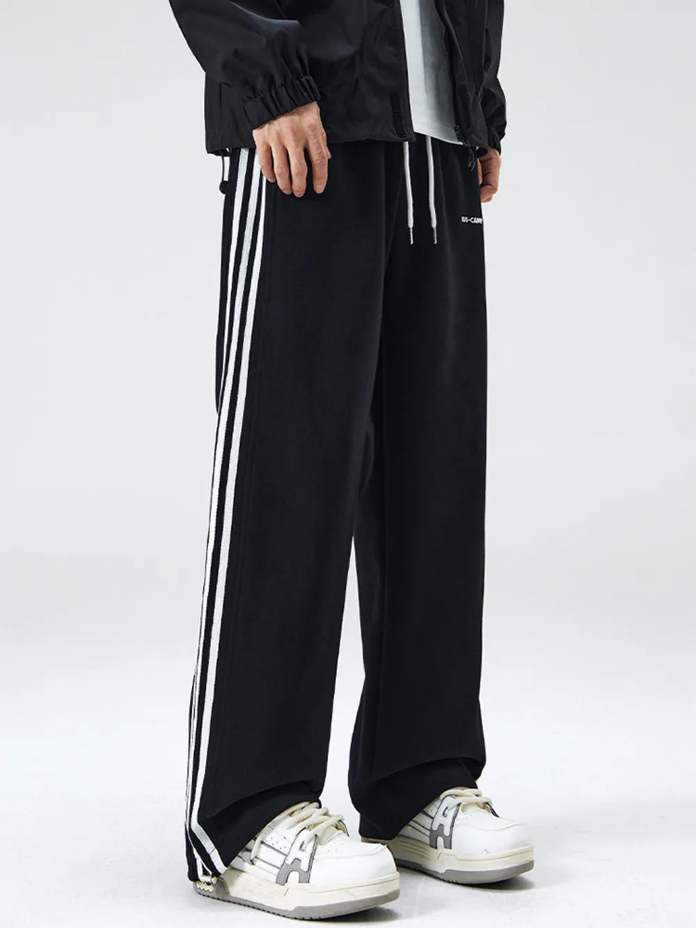 Black cotton sweatpants with white side stripes and drawstring waist.