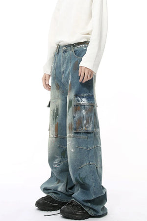 Artisan denim cargo pants in medium wash with paint splatters and wide legs.