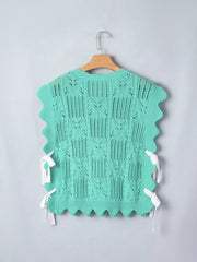 Green pointelle knit sweater with scalloped trim and side tie details.