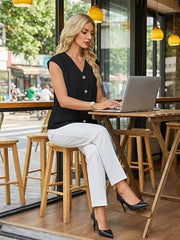 Black V-neck buttoned shirt with cap sleeves, styled with white pants and black heels.