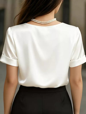 White satin shirt with cuffed sleeves and V-neck, styled with pearls