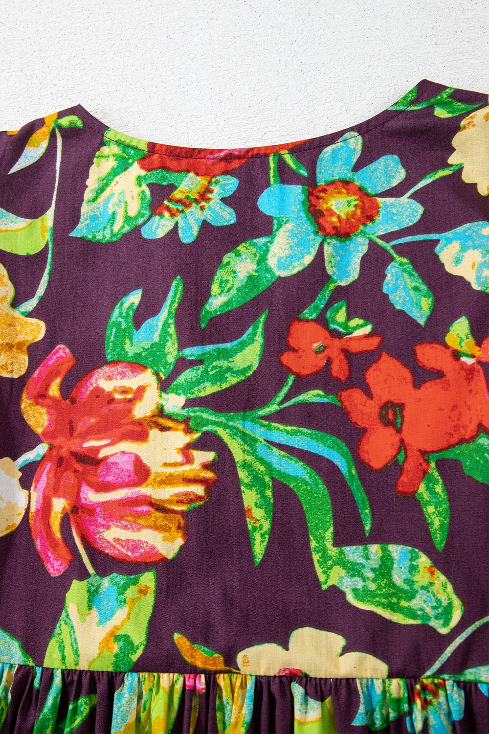 Embroidered floral babydoll blouse with a ruffled hem and round neckline.