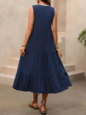 Navy midi dress with tiered skirt and ruffled hem, featuring a white scalloped neckline detail.