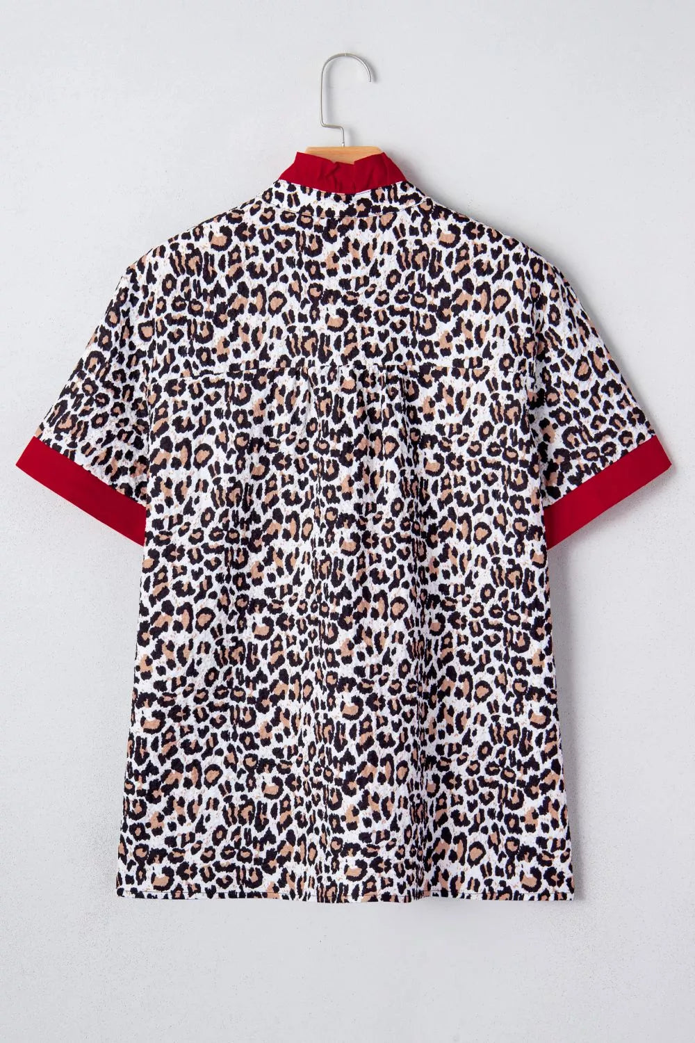 Leopard print polyester shirt with red collar and cuffs.