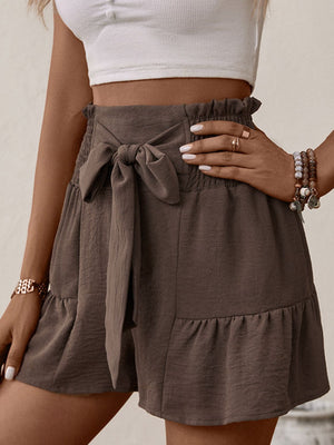Mocha smocked waist tie shorts with ruffled hem and tiered fabric detail.