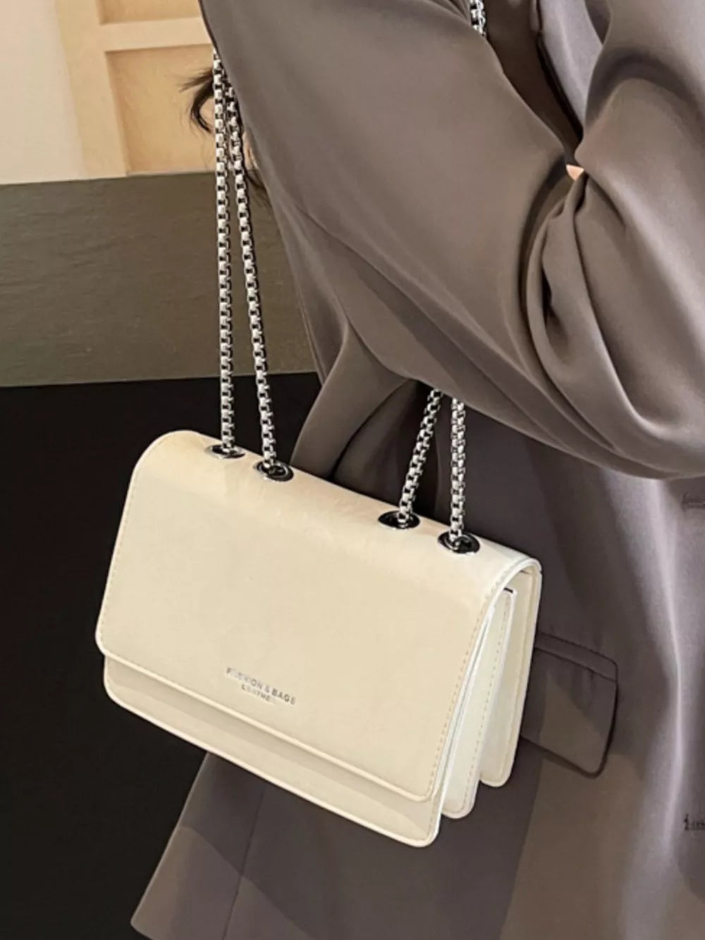 Beige leather shoulder bag with chain strap and crumpled texture detail.