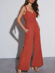 Orange-red tie-strap bodice wide-leg jumpsuit with smocked waist and pockets.
