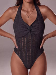Black lace halter bodysuit with twisted front detail and intricate patterned cutouts.