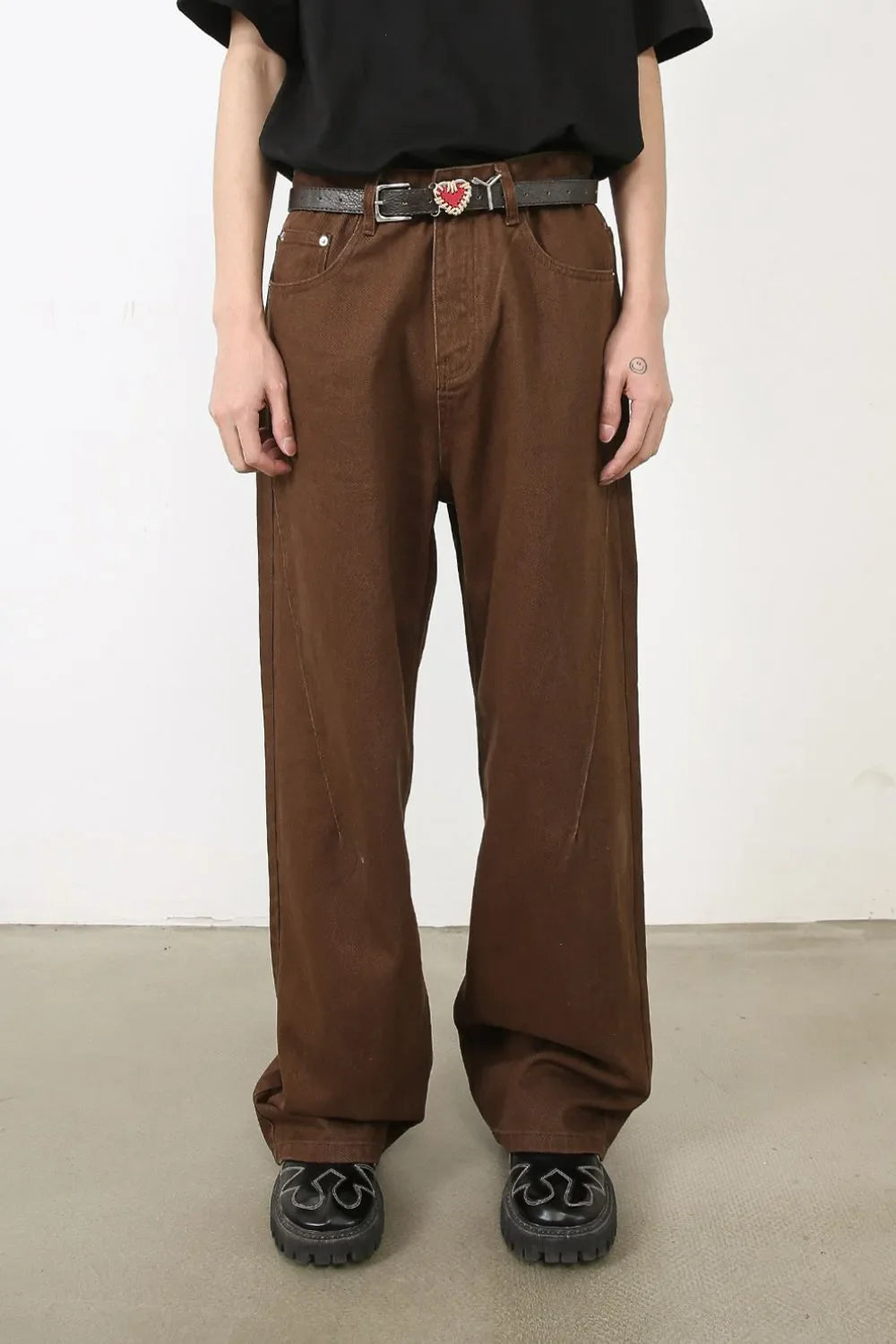 Brown wide-leg denim jeans with angled seams and a belt.