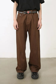 Brown wide-leg denim jeans with angled seams and a belt.