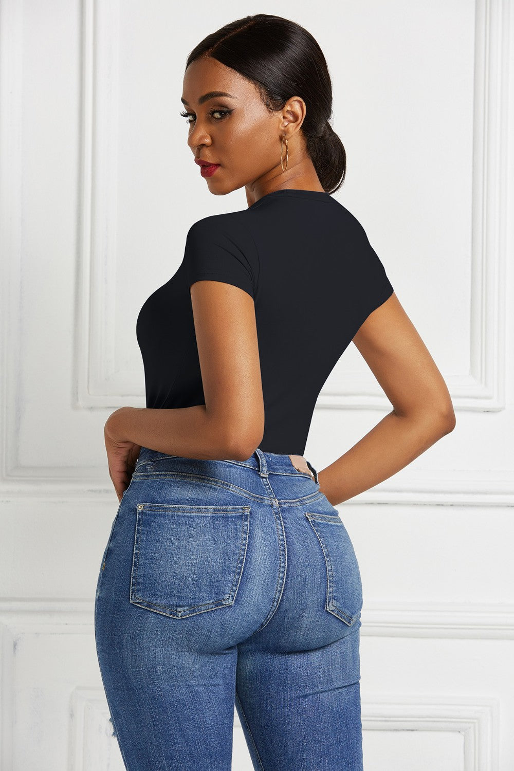 Black crew neck bodysuit with short sleeves, paired with blue denim jeans.