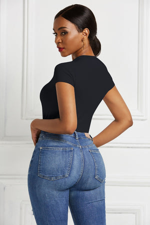 Black crew neck bodysuit with short sleeves, paired with blue denim jeans.