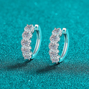 Silver moissanite cluster huggie hoop earrings with five sparkling stones.