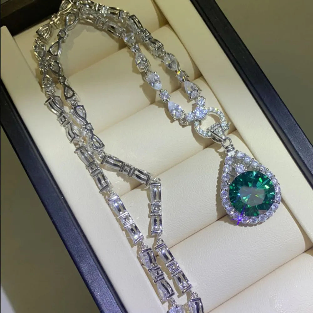 Silver moissanite halo pendant necklace with a teardrop emerald center stone.