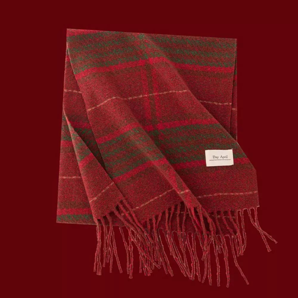 Cozy plaid scarf in red and green with fringe detail and a cream tag.