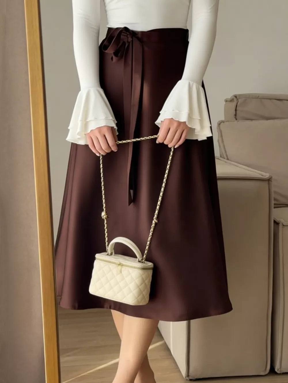Burgundy satin midi skirt with tie waist and bow detail, worn with a white ruffled sleeve top.