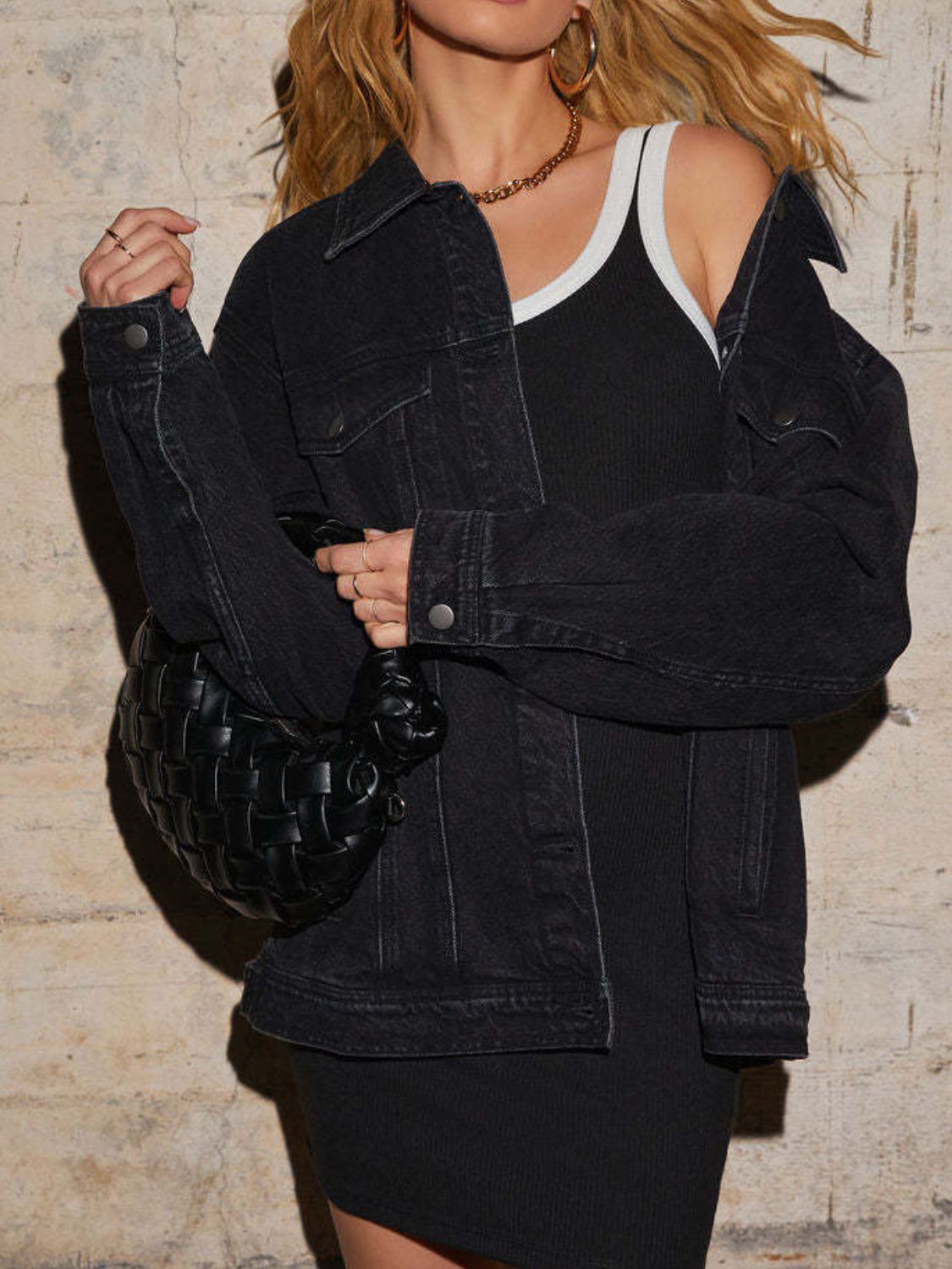 Black denim trucker jacket with collar, buttons, and chest pockets, styled with a black dress.