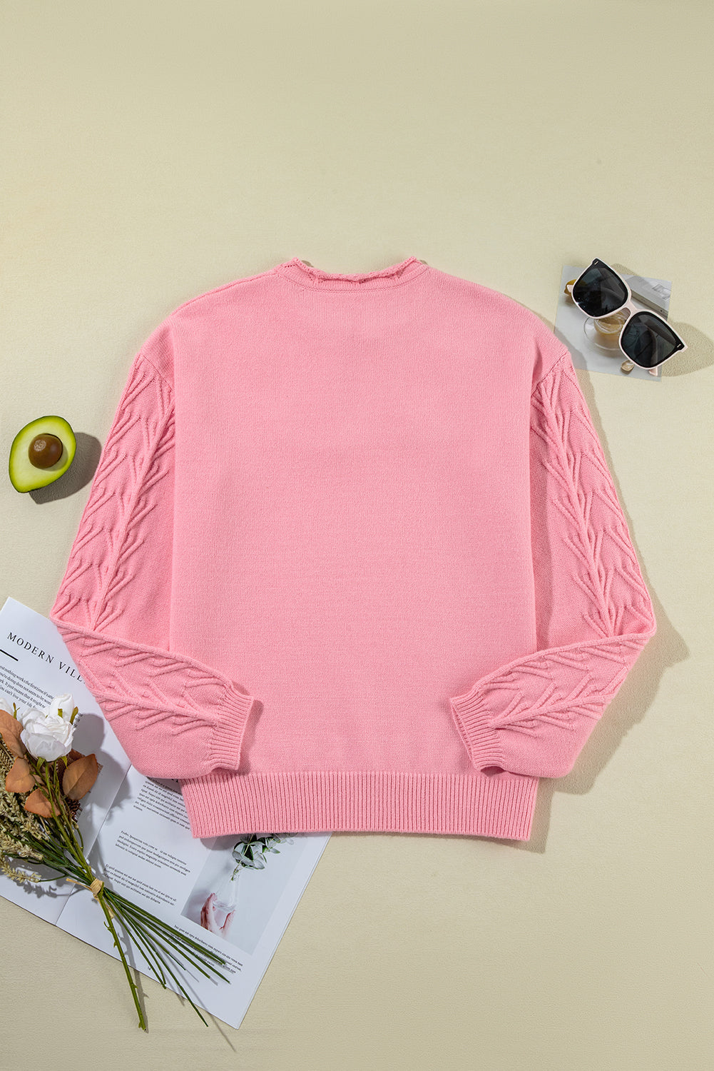 Blush pink knit sweater with cable knit sleeves and a frayed neckline.