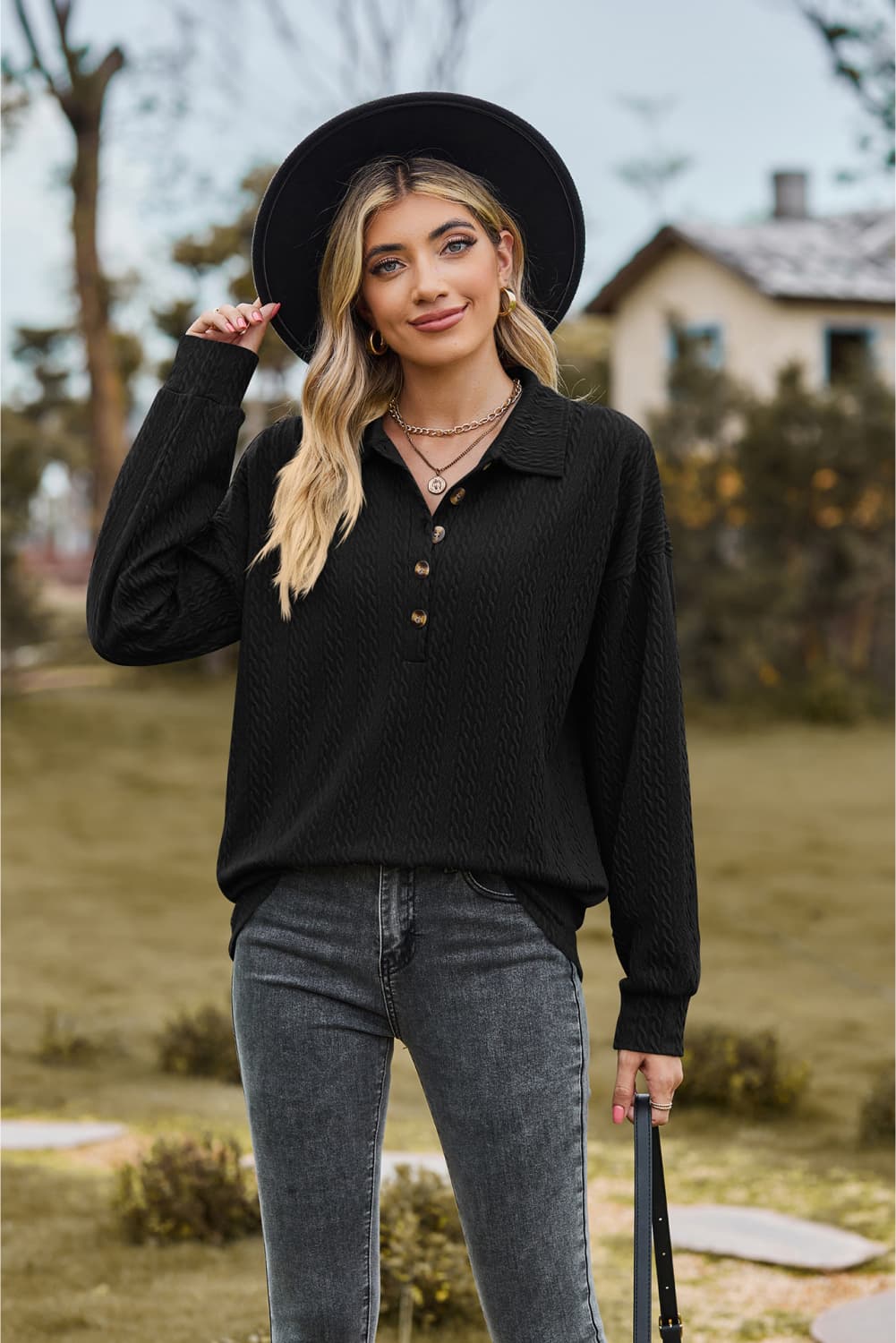 Black textured knit polo shirt with button detail and long sleeves.