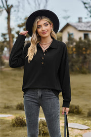 Black textured knit polo shirt with button detail and long sleeves.