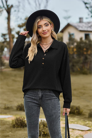 Black textured knit polo shirt with button detail and long sleeves.