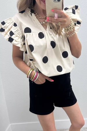 Cream cotton V-neck shirt with black polka dots and ruffled sleeves.