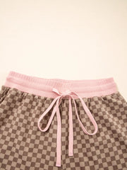 Brown checkerboard loungewear shorts with pink drawstring and waistband.