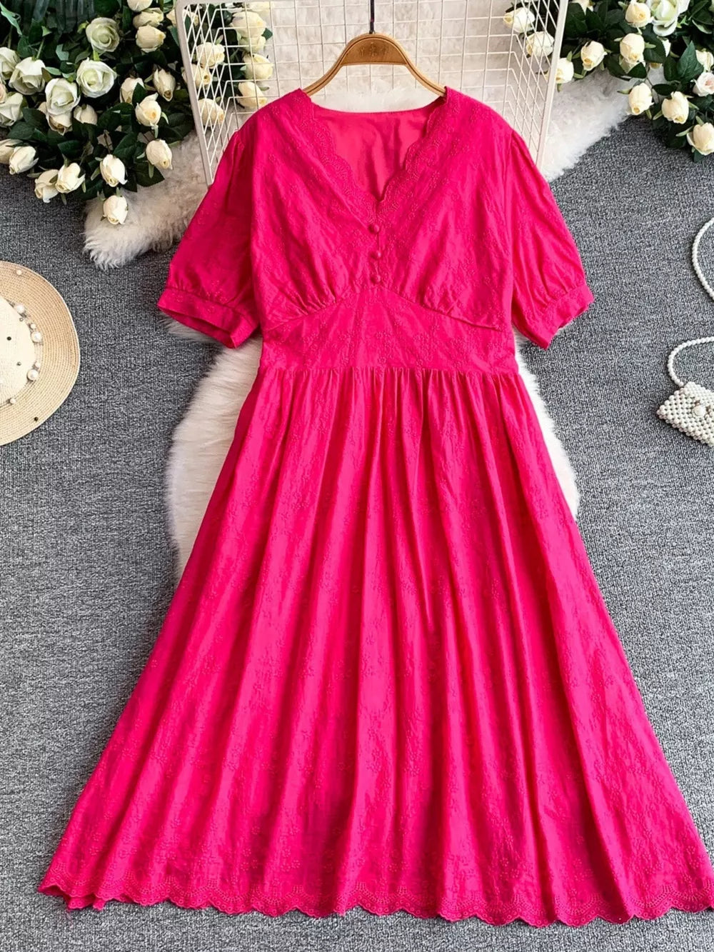 Pink lace-embellished A-line midi dress with V-neck and button detail.