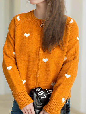 Orange zip-through knit sweater with white heart print, crew neck, and ribbed cuffs.