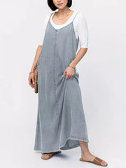Light blue washed denim maxi dress with V-neck and adjustable straps, worn over a white tee.