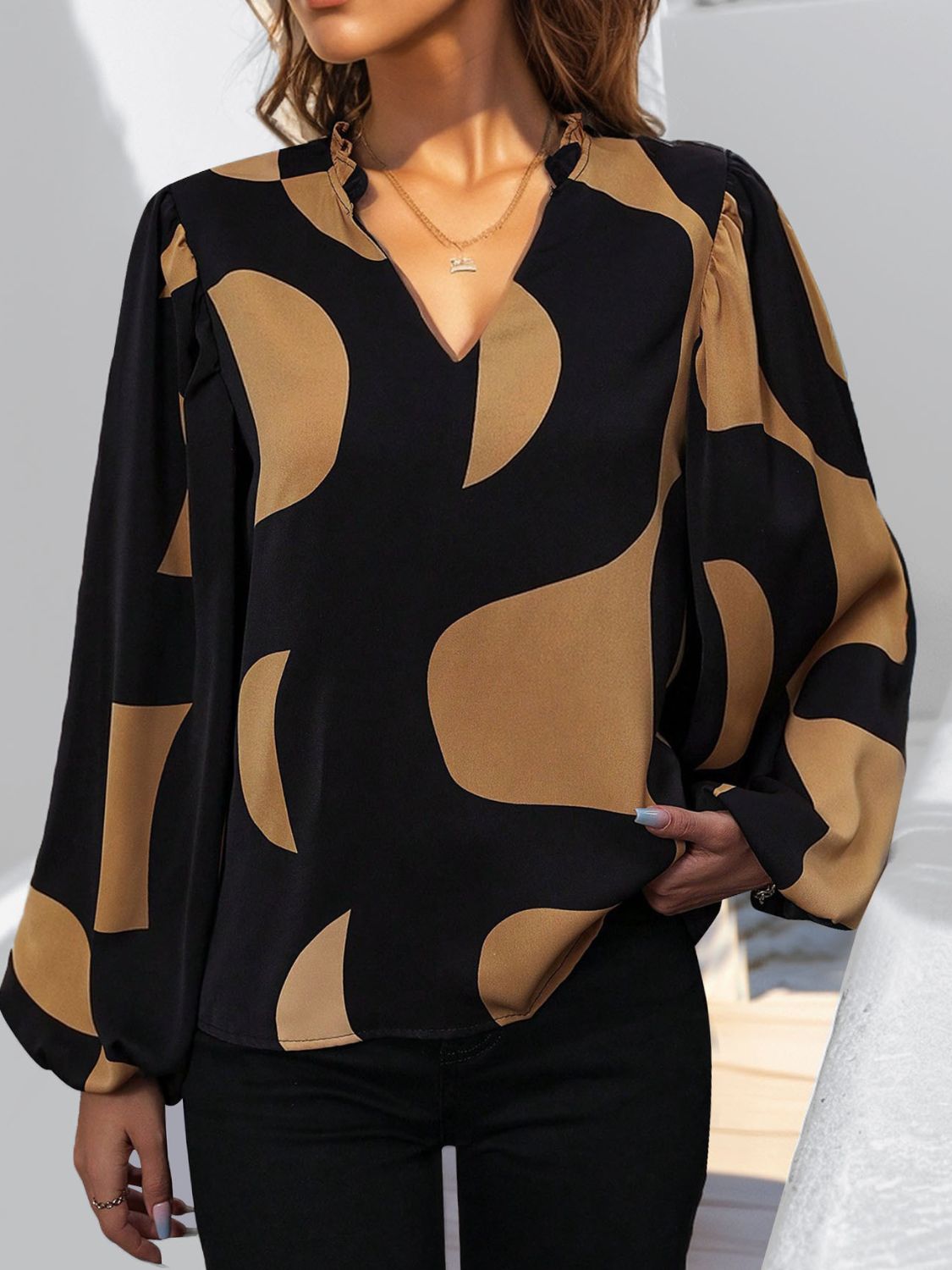 Black and tan geometric print blouse with voluminous sleeves and a V-neck.