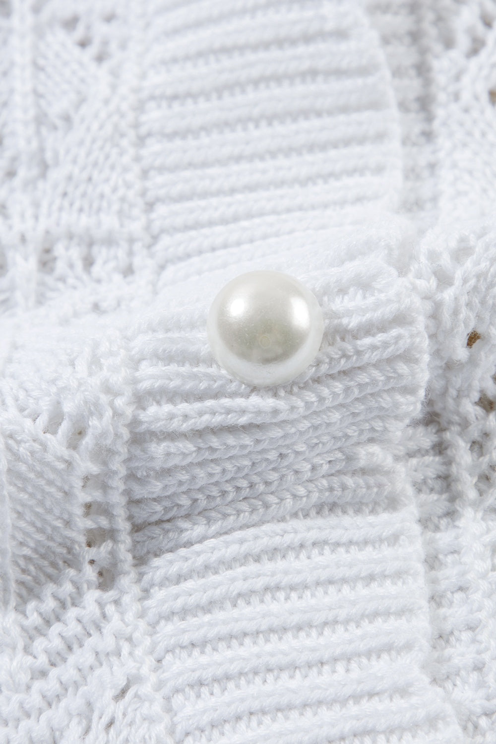 White openwork crochet cardigan with pearl button detail, acrylic knit.