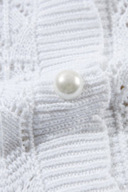 White openwork crochet cardigan with pearl button detail, acrylic knit.