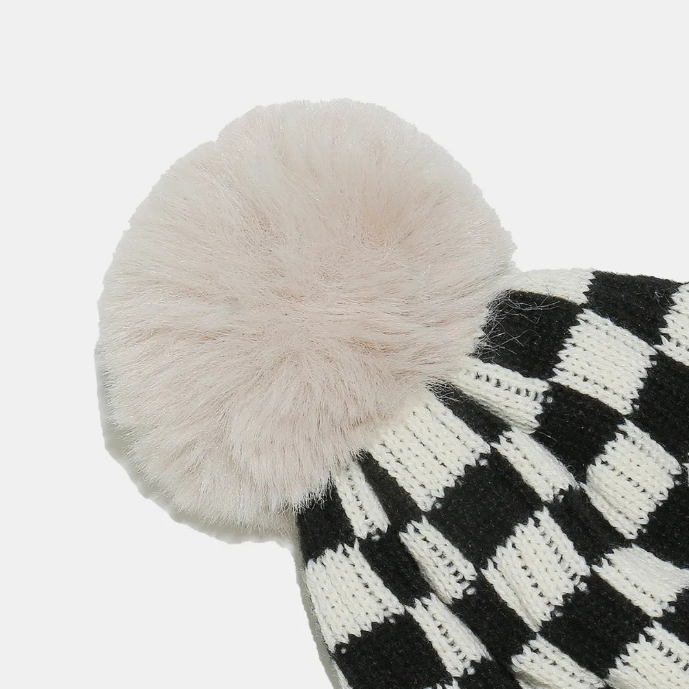 Checkerboard knit beanie with faux fur pom in black and white acrylic.