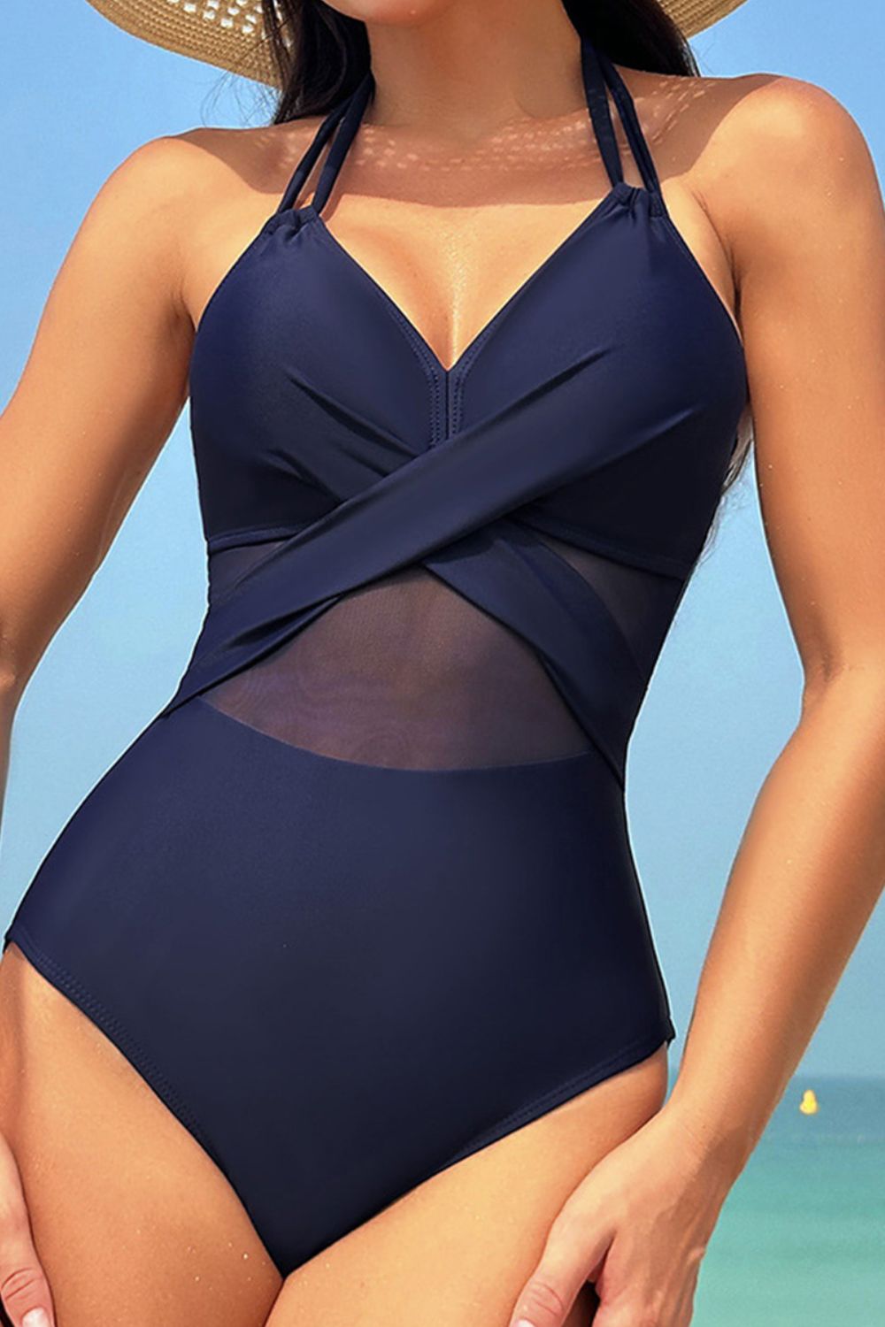 Dark blue one-piece swimsuit with crossover halter neckline and sheer mesh insets.