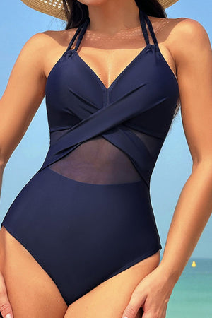 Dark blue one-piece swimsuit with crossover halter neckline and sheer mesh insets.