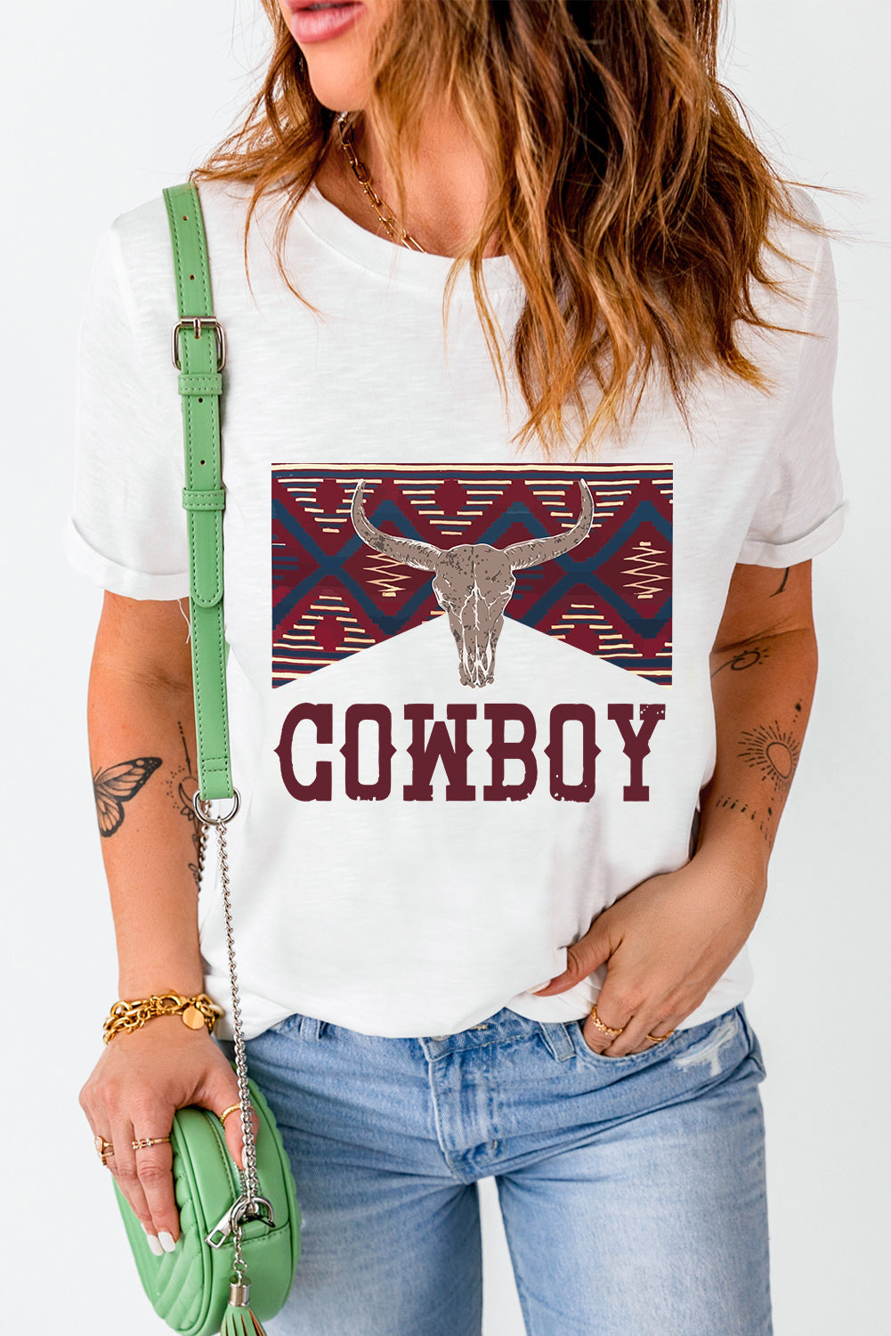 White graphic t-shirt with bull skull and cowboy text, featuring a geometric pattern.