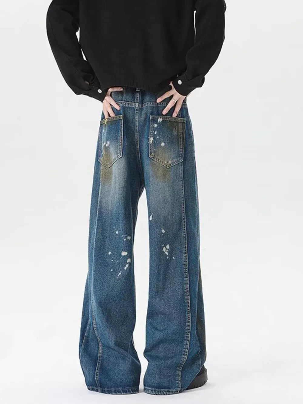 Men's plus-size wide-leg jeans in washed blue denim with paint splatters and distressed pockets.