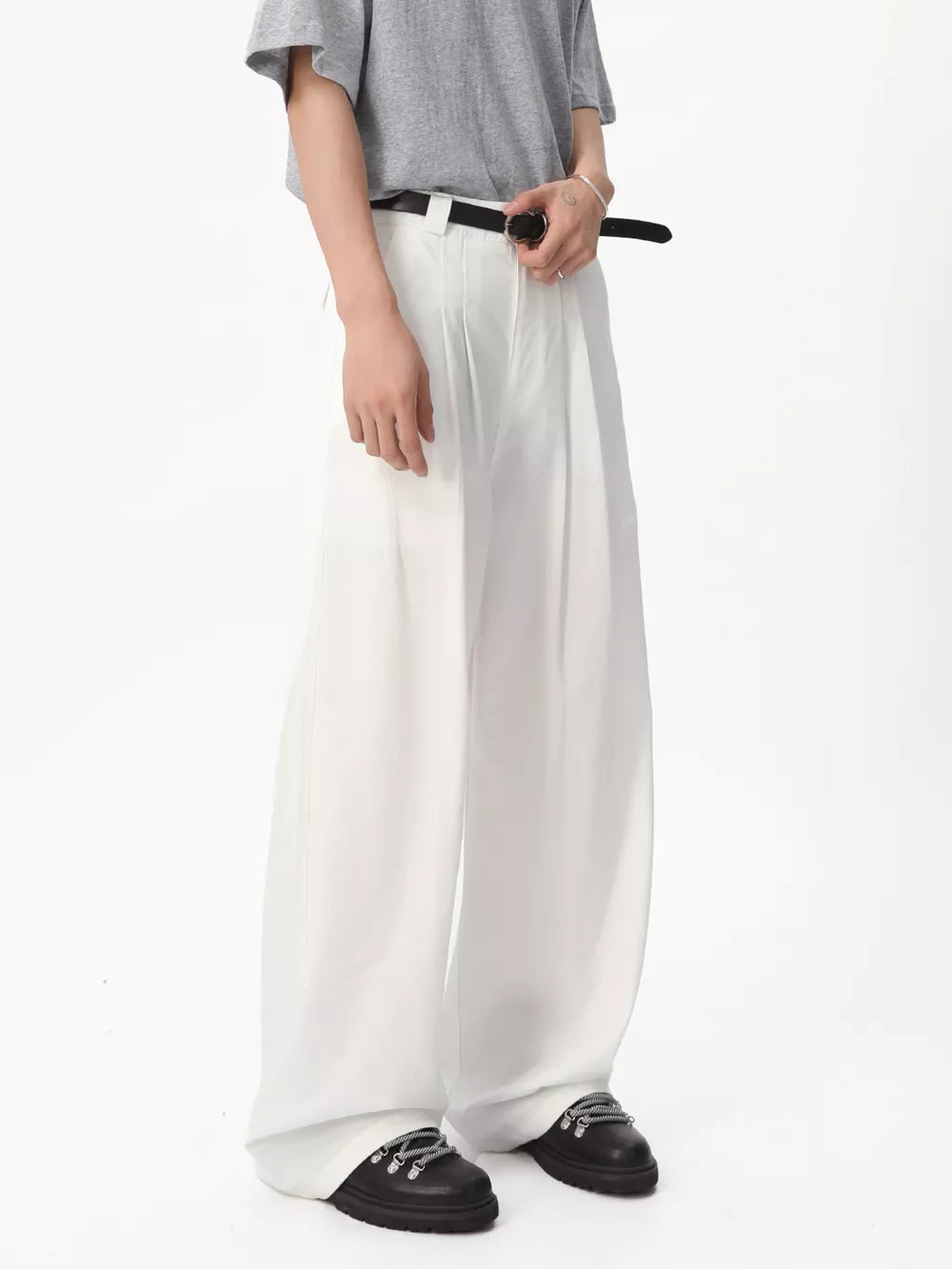 White relaxed wide-leg pleated sweatpants with a belt and black boots.