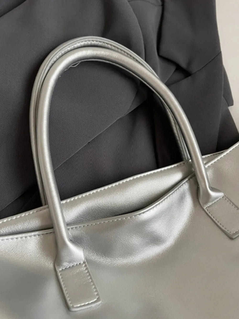 Silver metallic tote bag with top handles and a chic, casual style.