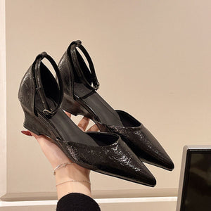 Black pointed-toe ankle strap wedge heels with adjustable buckle.