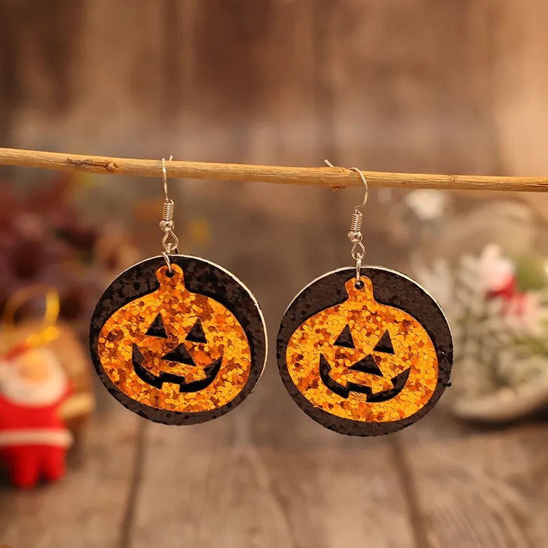 Glitter pumpkin Halloween dangle earrings in tangerine with black accents.