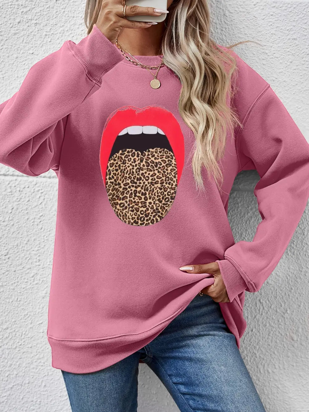 Blush pink sweatshirt with a bold red mouth and leopard print tongue graphic.