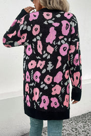 Black floral jacquard longline knit cardigan with pink and grey flowers, long sleeves, and ribbed trim.